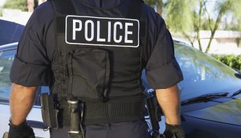 Police officer in bulletproof vest outdoors, back view