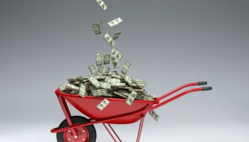 Dollars falling into red wheelbarrow