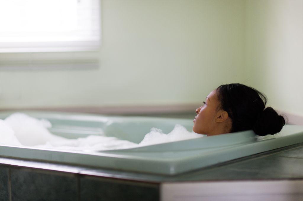 Young woman relaxing in bubble bath gazing through window