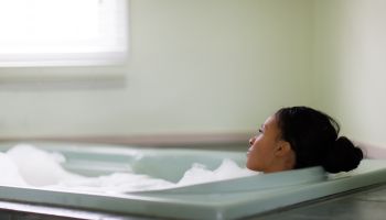 Young woman relaxing in bubble bath gazing through window