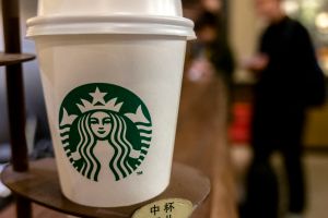 A Starbucks coffee cup on table. Starbucks is growing fast...