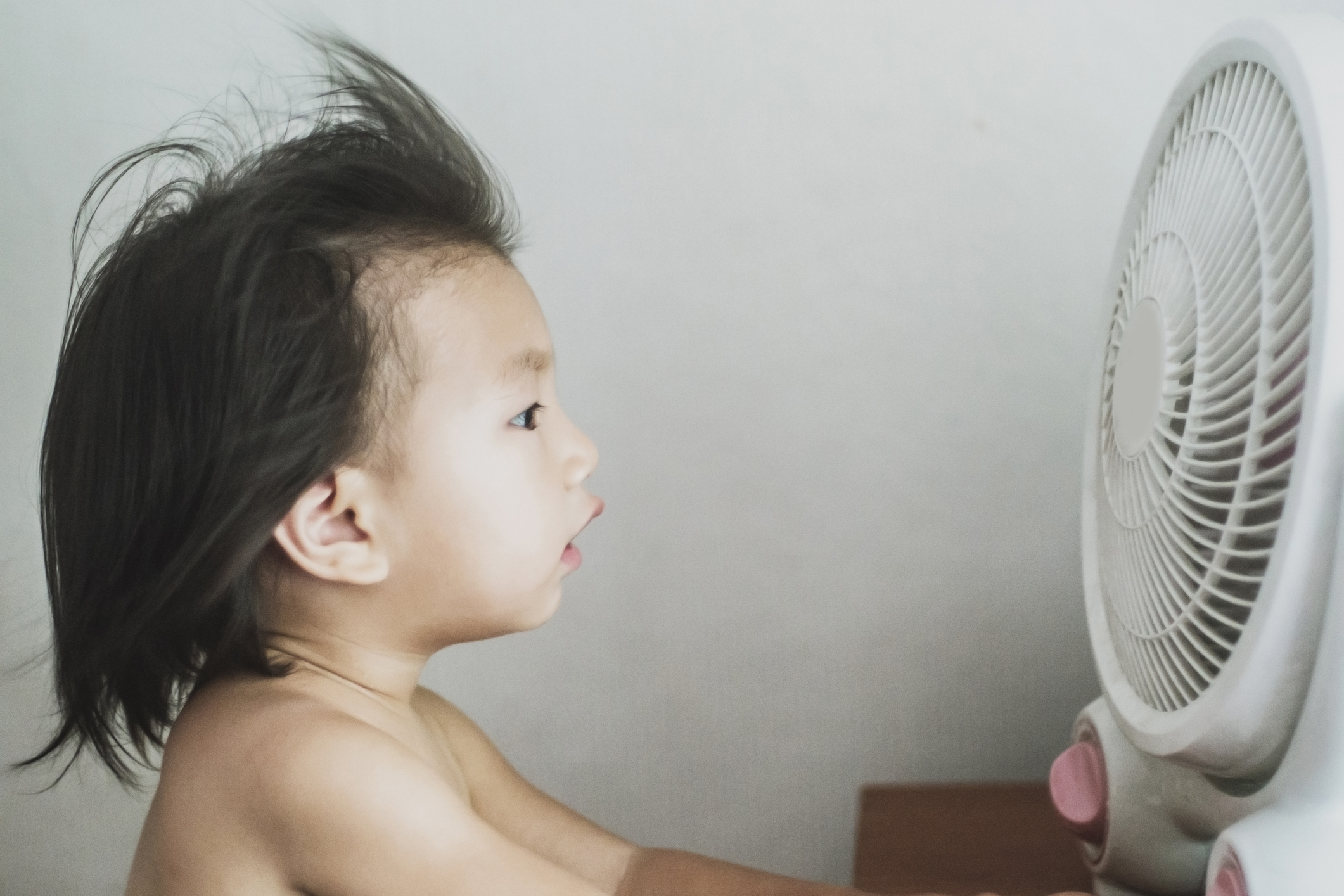 Cute 3-5 years girl against the blowing ventilator