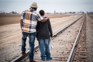 Father and son standing on train track with trumpet