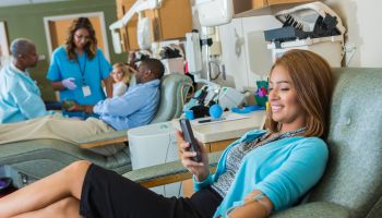 Confident businesswoman passes the time while donating blood