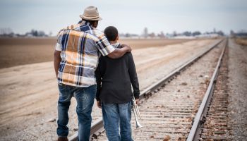 Father and son standing on train track with trumpet