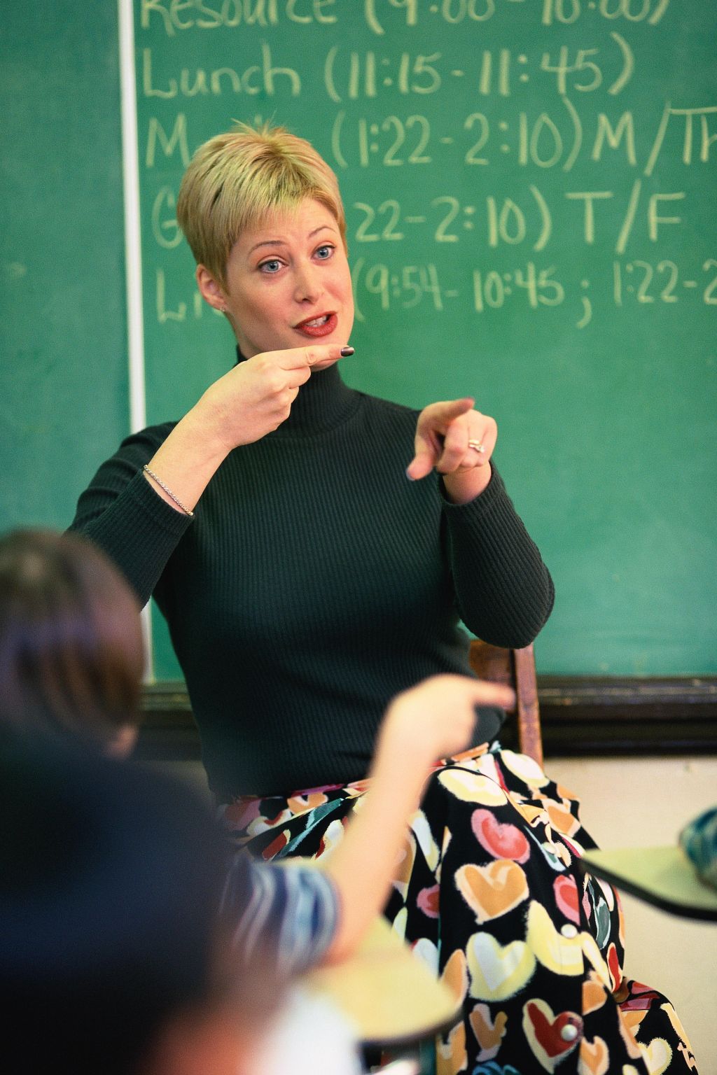 Teacher talking and pointing at front of classroom