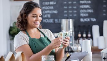 Young female barista counts money from tips jar