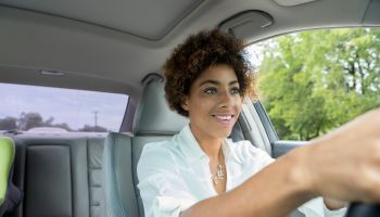 Smiling young woman driving her car on a sunny day