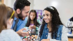 Cheerful teenage girl laughs with STEM teacher in class
