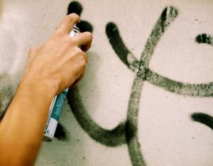 Close-up of a human hand spraying paint on a wall