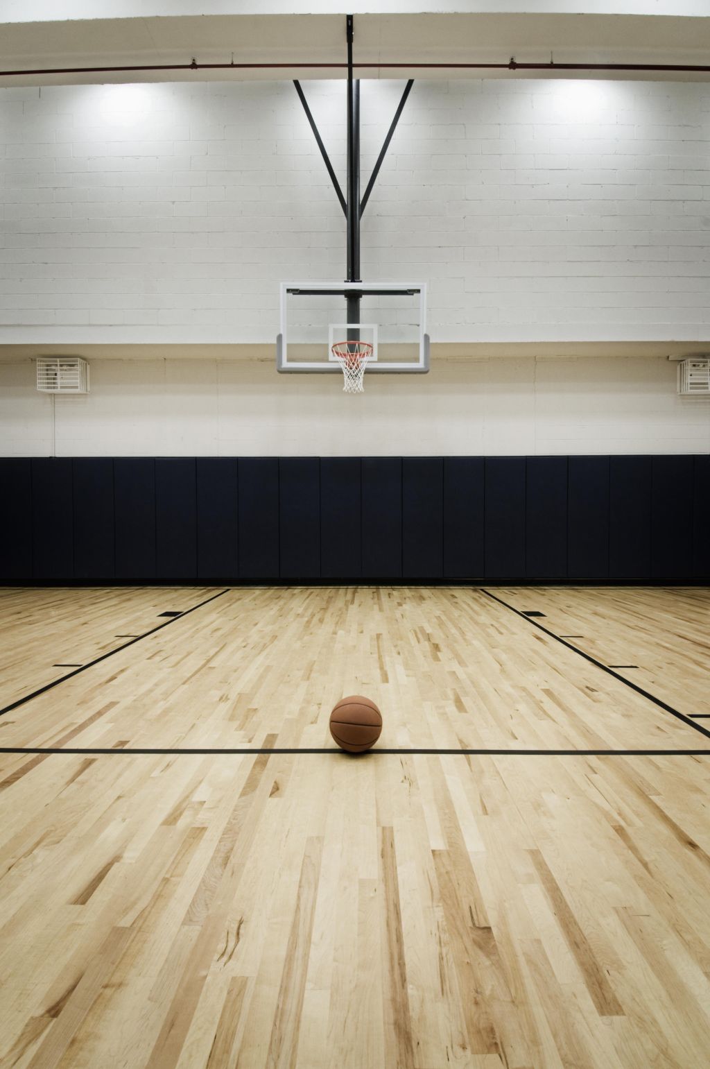 A basketball sits on the free throw line.