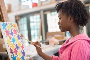 Young artist painting on easel