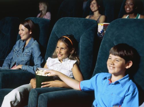 Children watching a movie in a movie theatre and eating popcorn