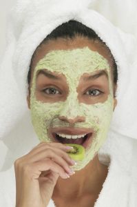 Portrait of a young woman wearing a facial mask eating a slice of kiwi