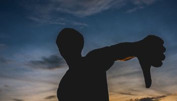 Silhouette Man Gesturing Thumbs Down Against Sky During Sunset