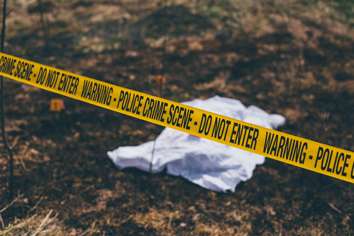 Dead body on the ground behind a cordon tape