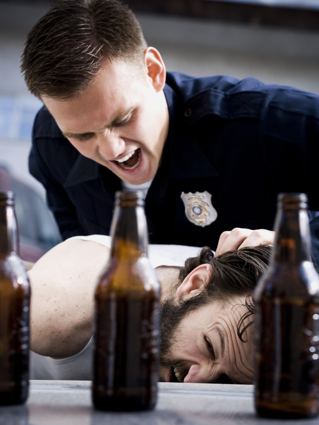 Police officer arresting man lying down with beer bottles