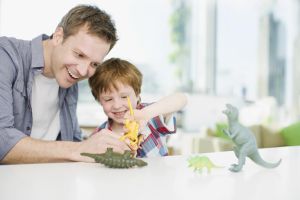 Father and son playing with plastic dinosaurs