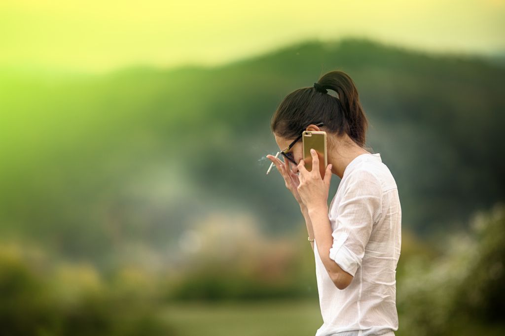 Woman smoking and talking on cell phone outdoors