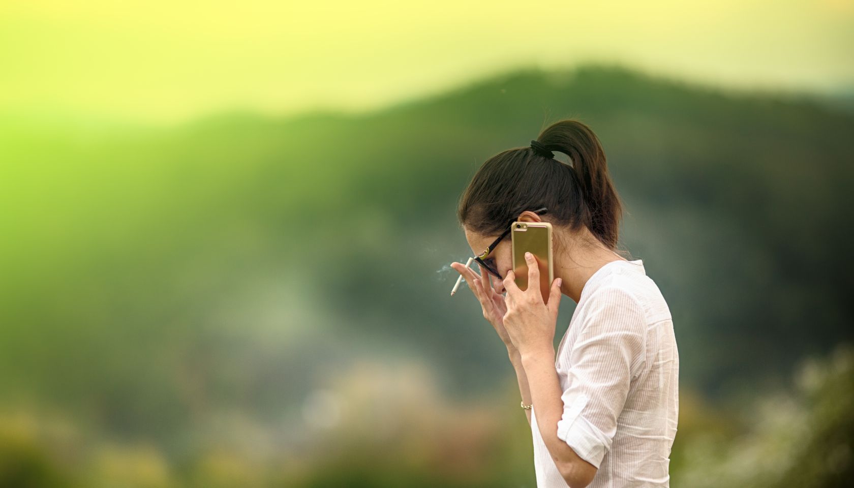Woman smoking and talking on cell phone outdoors