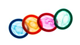 High Angle View Of Multi Colored Condoms Against White Background