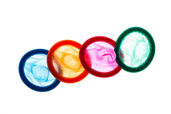High Angle View Of Multi Colored Condoms Against White Background
