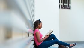 Young woman reading a book outside a campus building