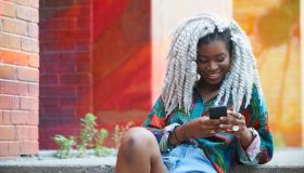 Smiling Black woman texting on cell phone