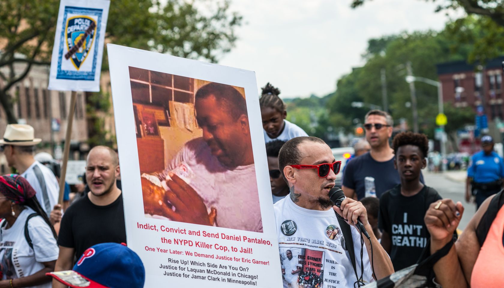 Rally participants hold signs near the site of Eric Garner's...