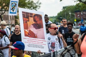 Rally participants hold signs near the site of Eric Garner's...
