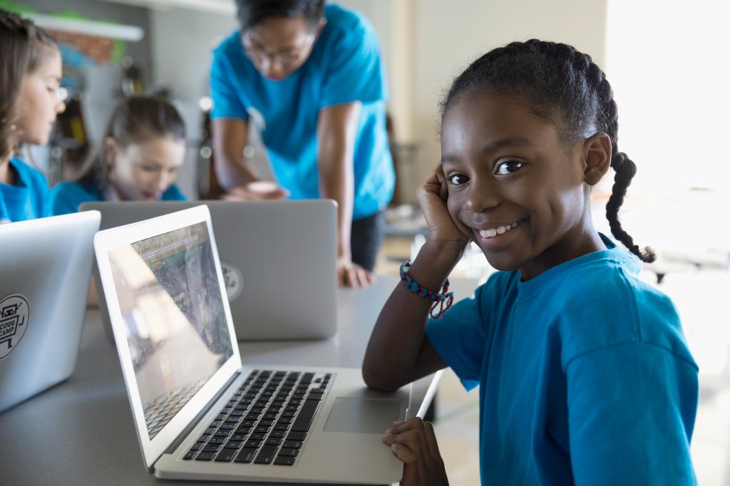 Portrait confident, smiling pre-adolescent girl using laptop in classroom