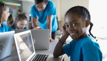 Portrait confident, smiling pre-adolescent girl using laptop in classroom