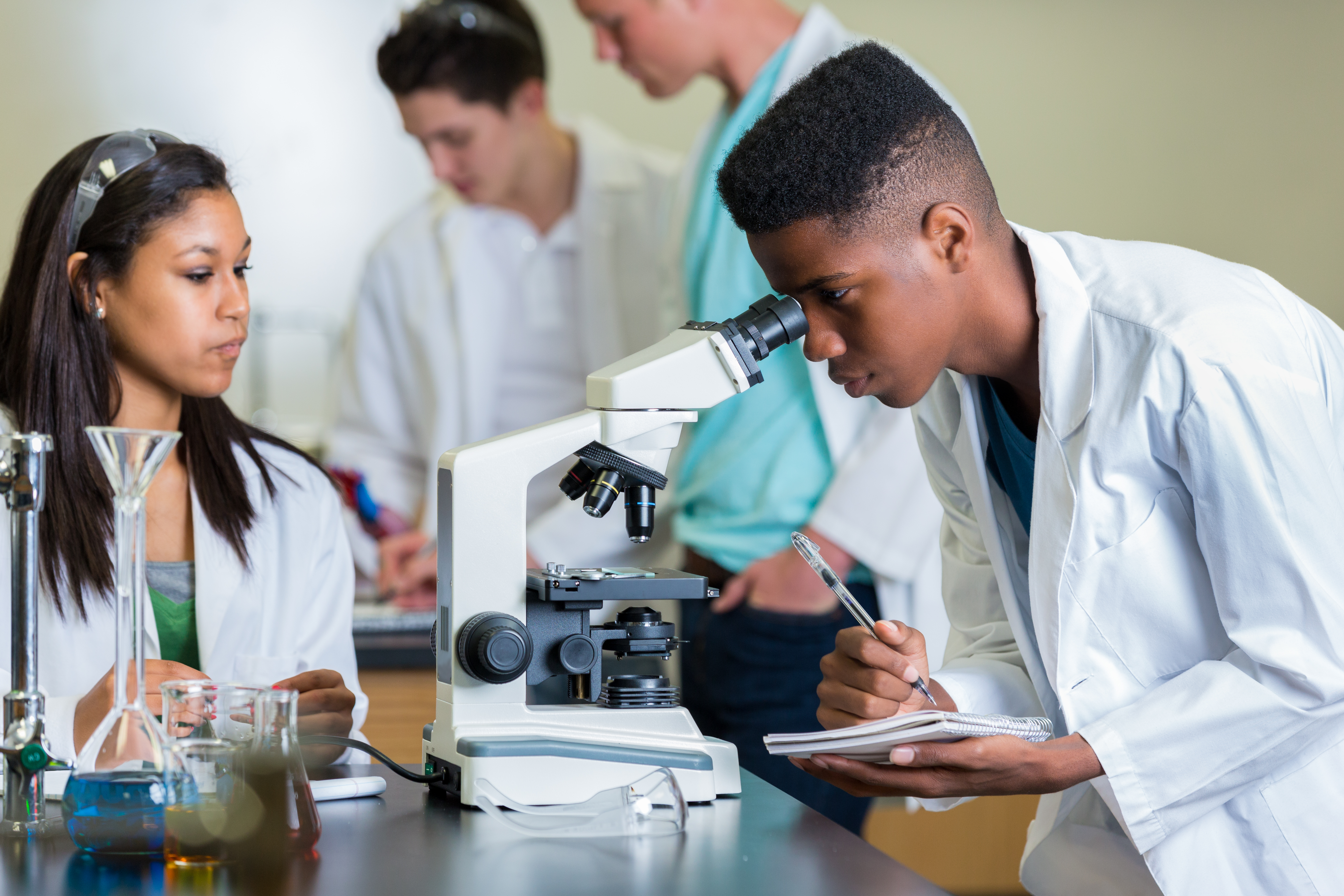 African American high school student record observations in science lab