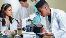 African American high school student record observations in science lab