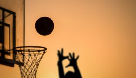 Silhouette Person Taking A Shot By Basketball Hoop Against Sky During Sunset
