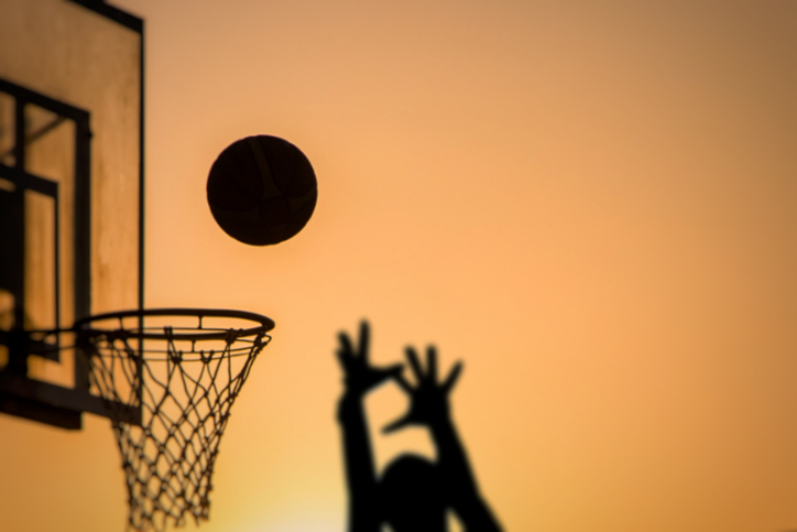 Silhouette Person Taking A Shot By Basketball Hoop Against Sky During Sunset