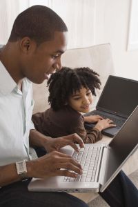 Father and daughter using laptop computers