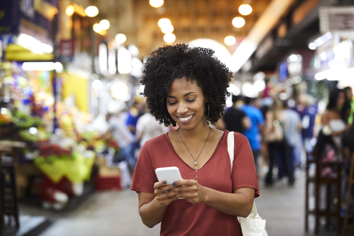 Smiling woman using smart phone at supermarket