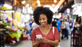 Smiling woman using smart phone at supermarket