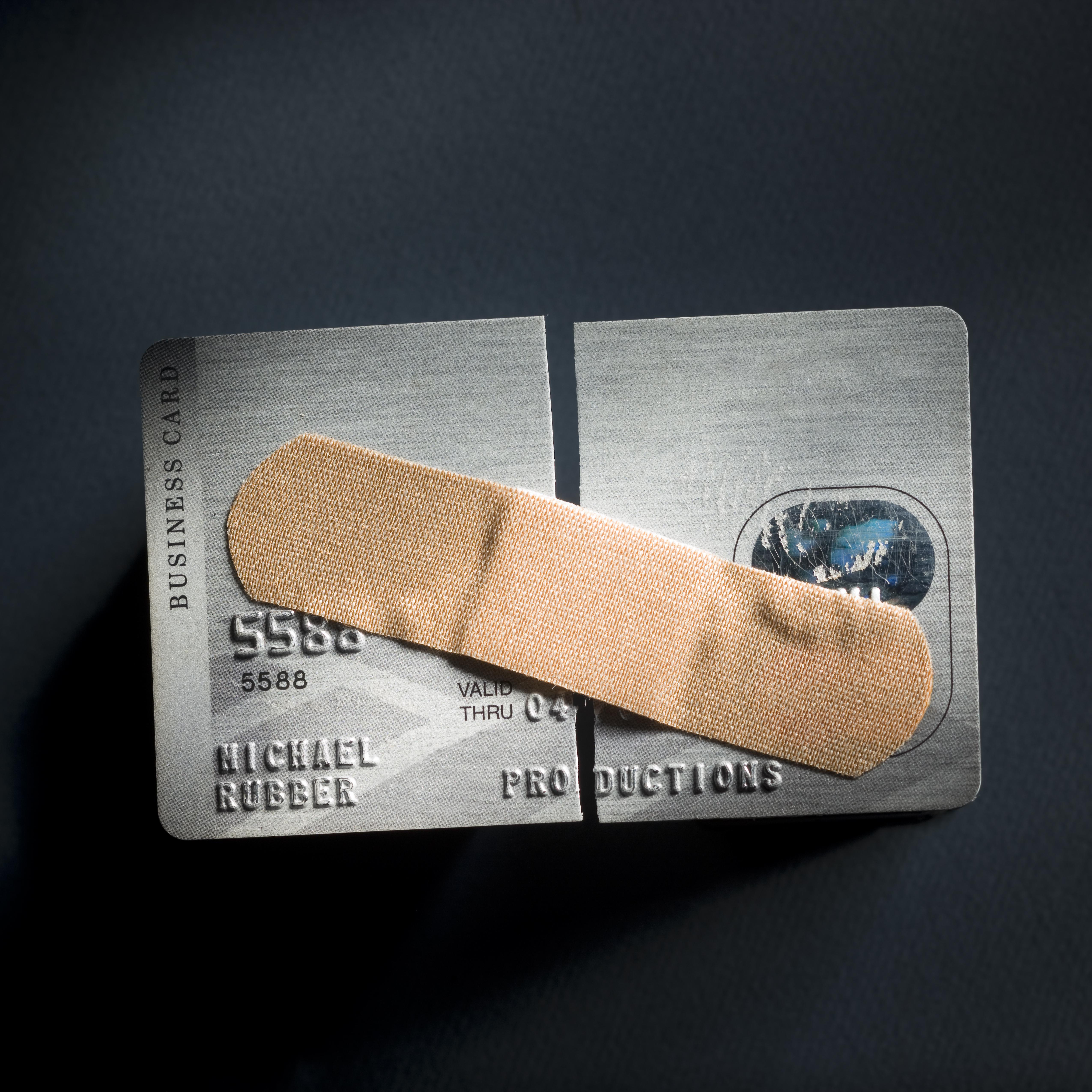 credit card cut in half with a band-aid holding it together