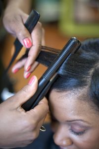 Woman getting hair straightened in salon