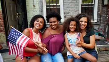 Portrait of smiling women and girl posing with American flag