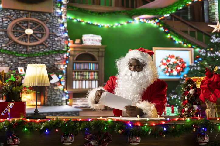 Father Christmas reading letters and lists in his festive workshop