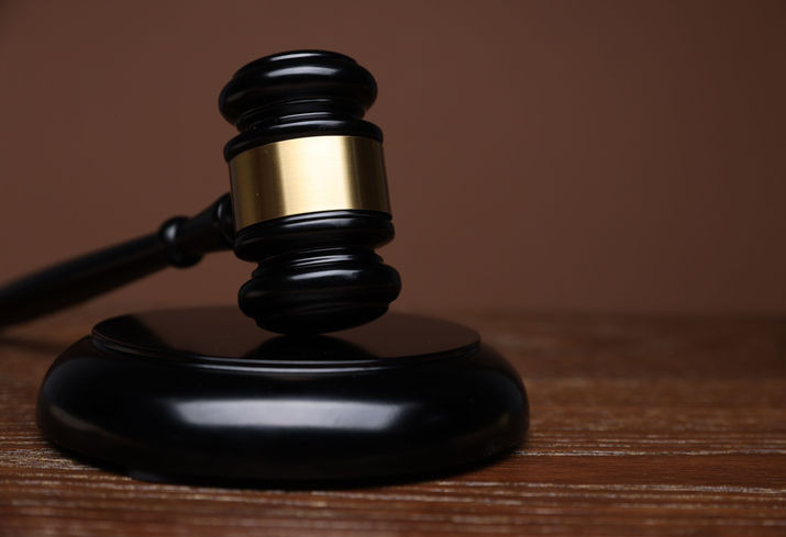 Judge's gavel and sound block on wooden table against brown background, closeup. Space for text