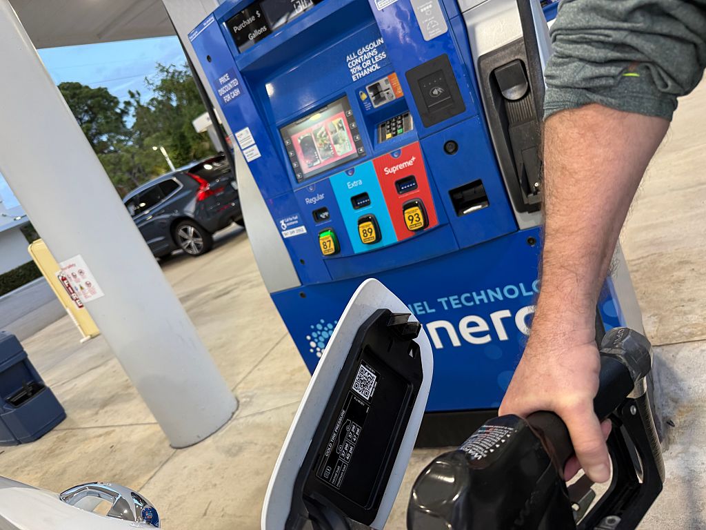 Hand on nozzle in car filling up gas at Mobil gas station, Palm Beach Gardens, Florida