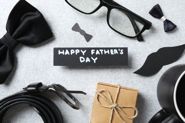 Father's Day concept. Top view photo of giftbox, elegant tie, glasses, belt and cup of coffee on grey background